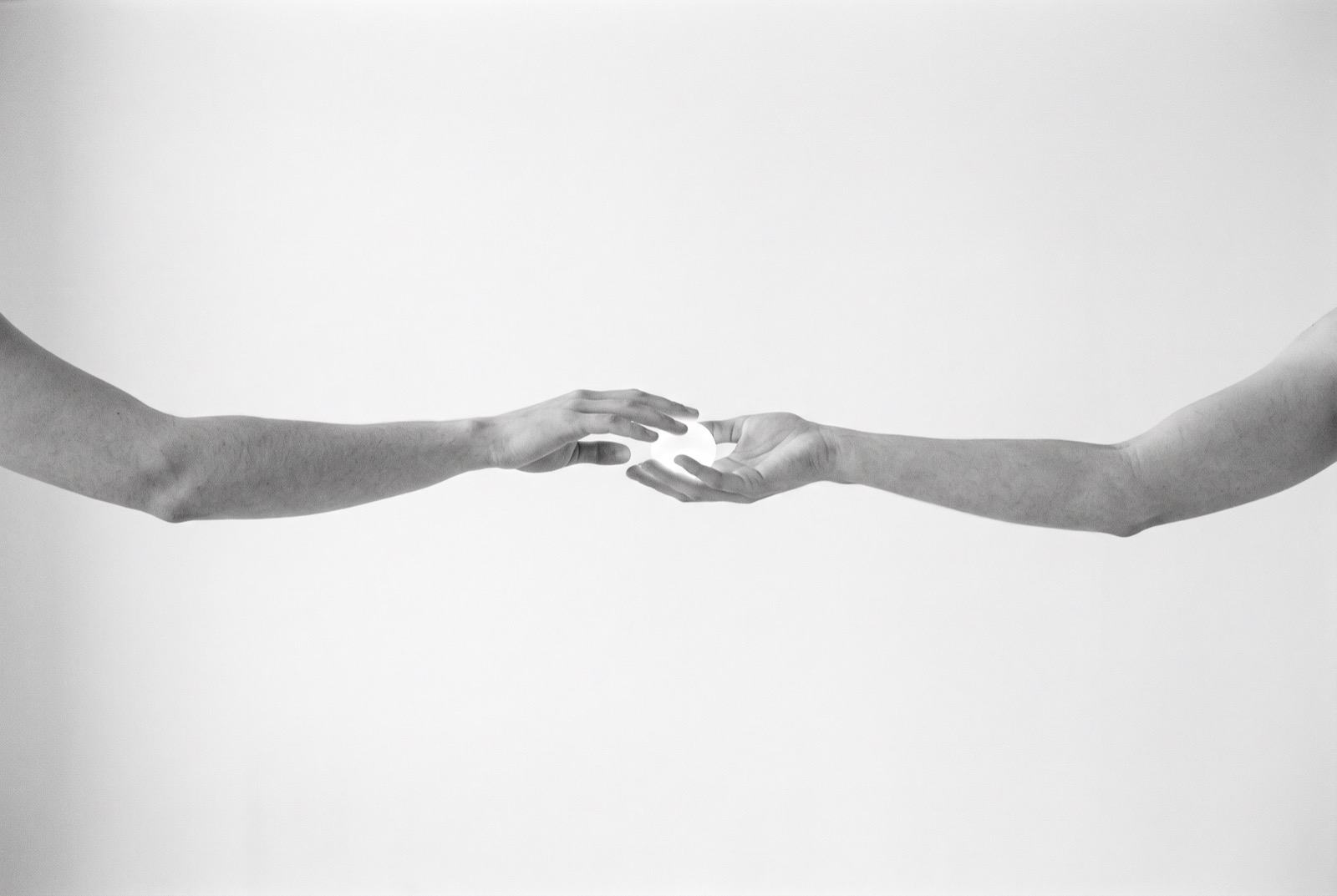 One hand passing a small light to another